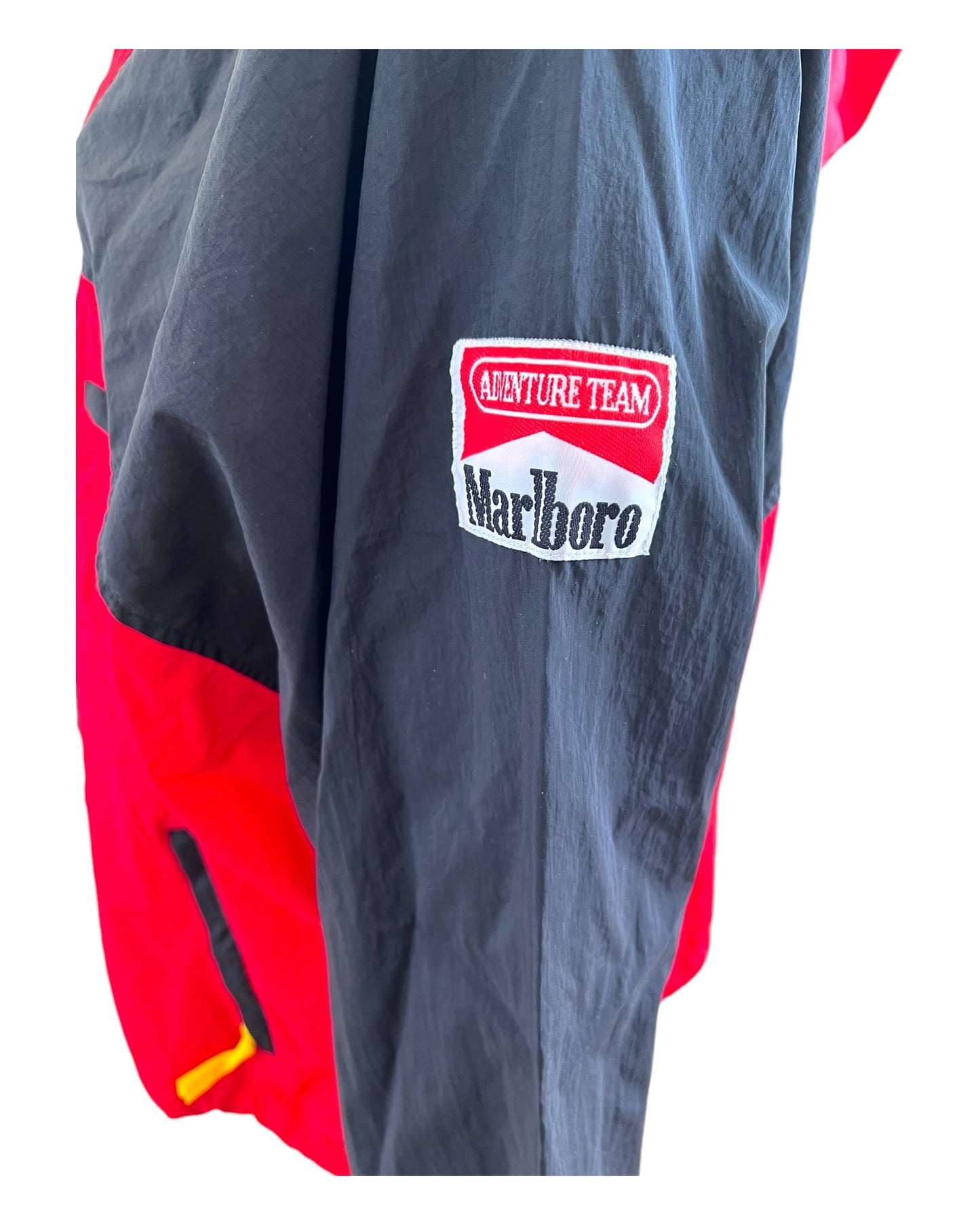 Vintage 1990s Marlboro Adventure Team Red and Black Nylon Windbreaker Jacket. Image depicts classic Marlboro Cigarettes logo on the sleeve.