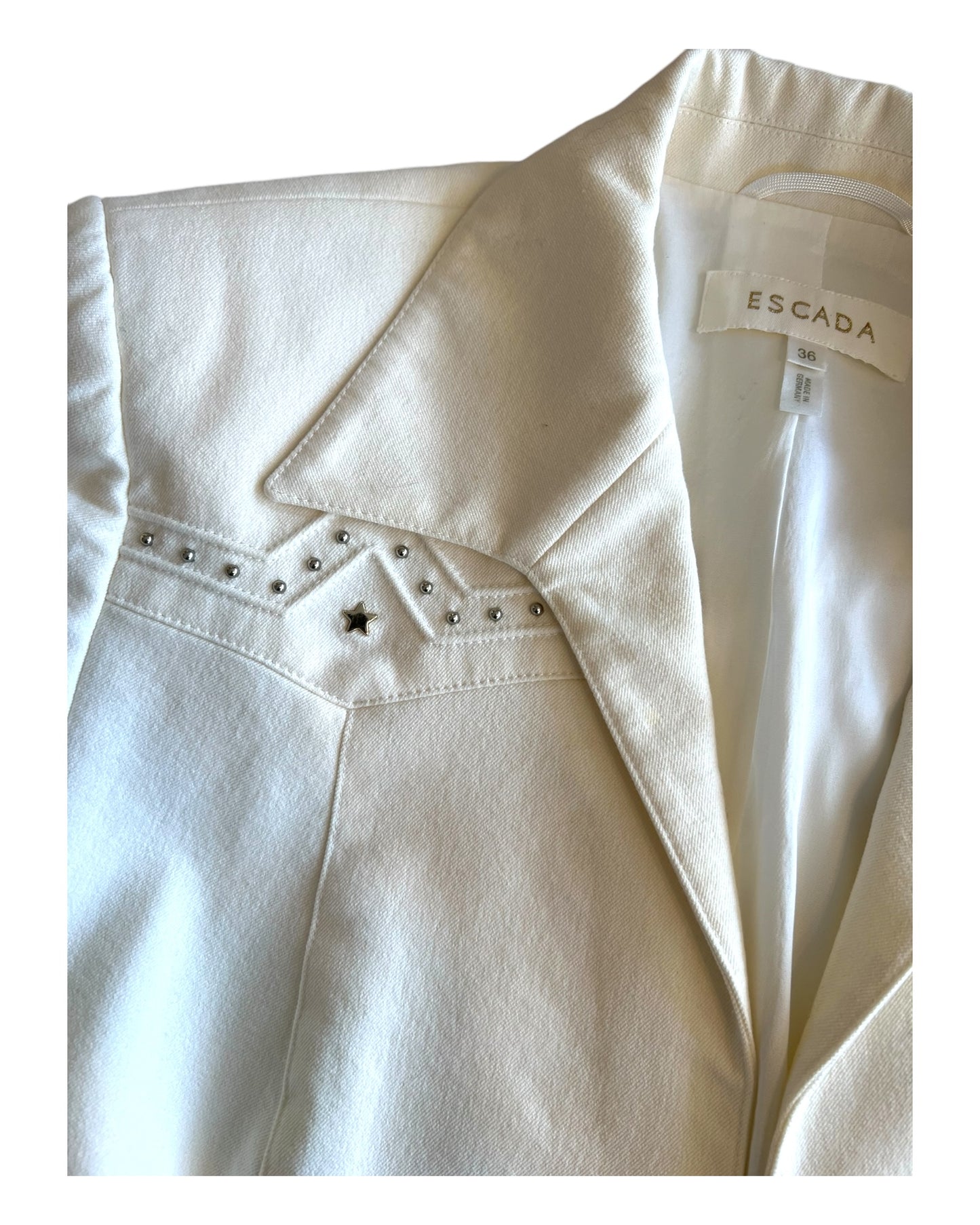 Vintage 2000 Escada white denim skirt suit. Image depicts a close-up of one of the embellishments on the blazer. It includes a silver-tone metal star with metal balls around it.