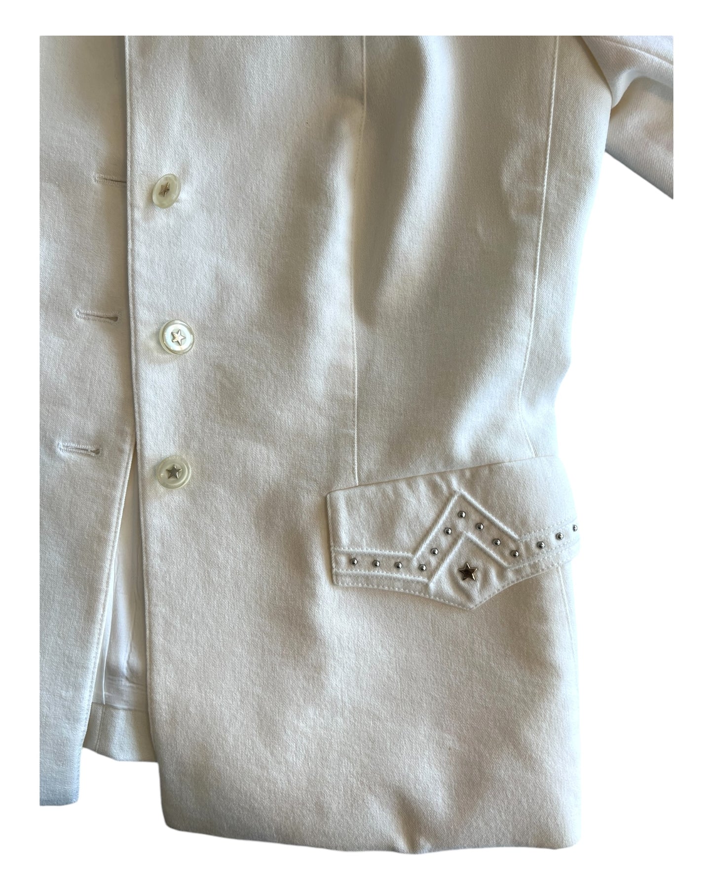 Vintage 2000 Escada white denim skirt suit. Image depicts a close-up of one of the embellished pockets on the blazer. It includes a silver-tone metal star with metal balls around it. image also shows the buttons on the jacket which are mother of pearl with a star in the center.