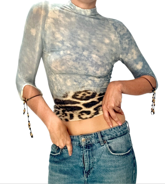 Person wearing a tie-dye long-sleeve top with a leopard print waistband and blue jeans.