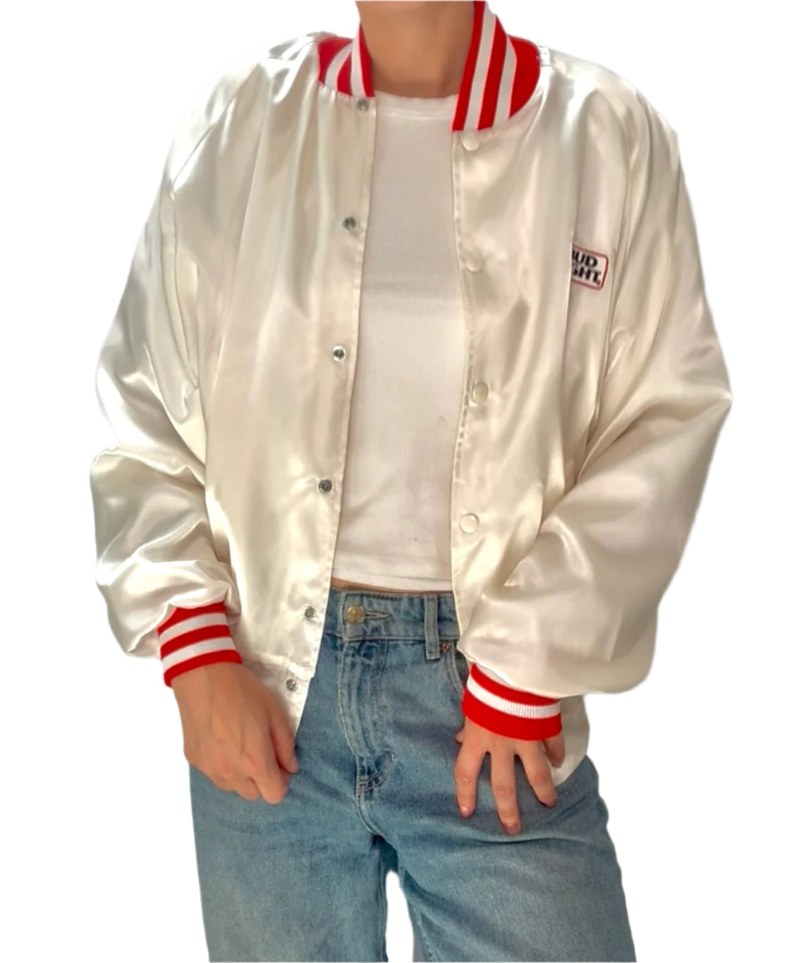 Person wearing a white satin jacket with red accents and blue jeans on a plain background