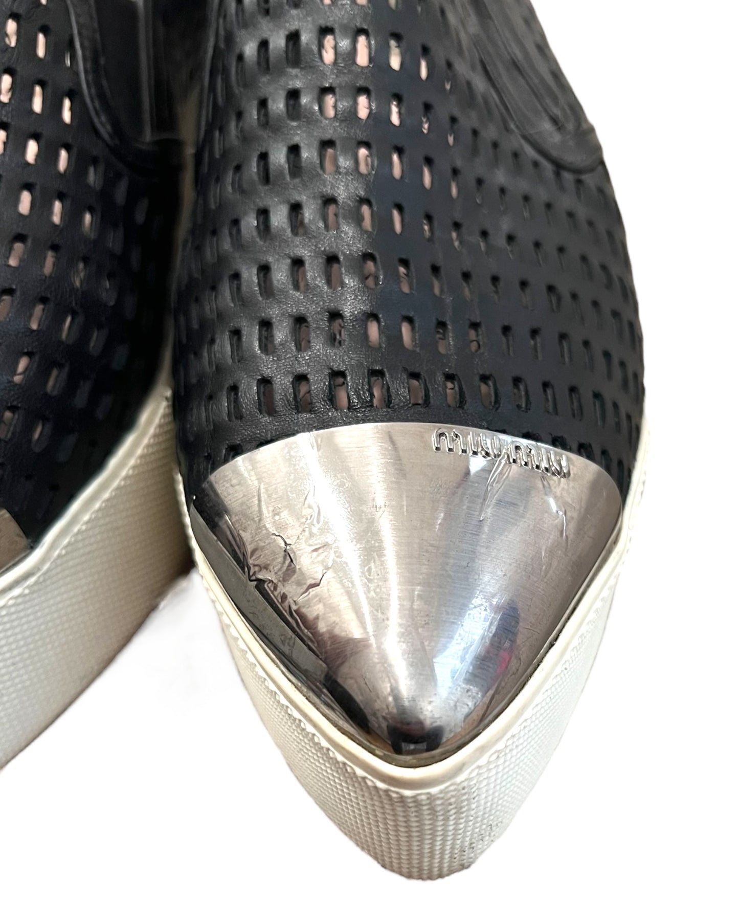 Pre-loved Miu Miu leather platform loafers. Shoes feature a leather mesh body with a silver-toned metal toe tip. Platform is approximately 2 inches in height. Image depicts the metal peeling on the toe of one of the left shoe. 