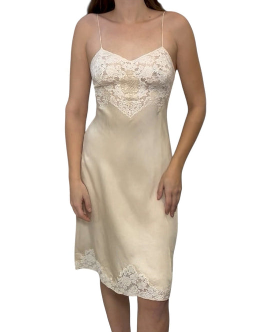 Woman wearing a beige slip dress with lace details on a white background