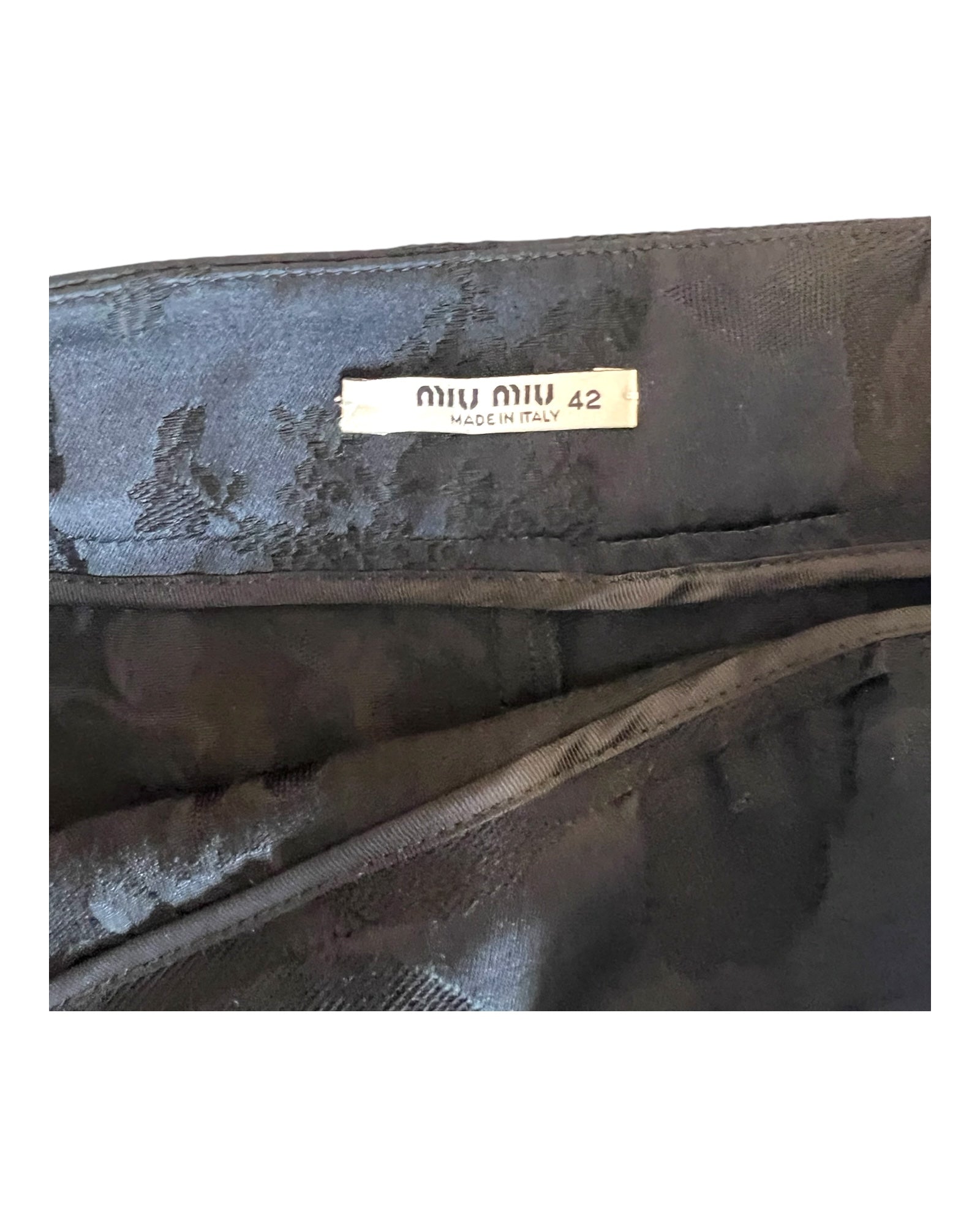 Vintage Miu Miu black skirt with a baroque pattern. Image depicts a close-up of the brand and size tag.