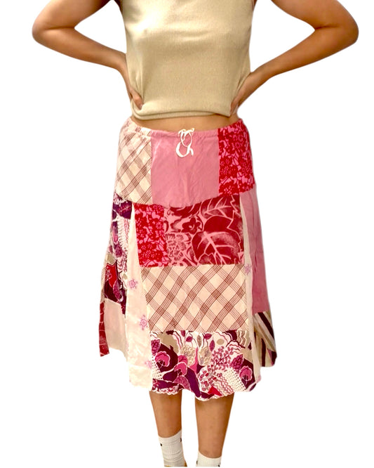 Person wearing a patchwork skirt with floral and plaid patterns on a white background