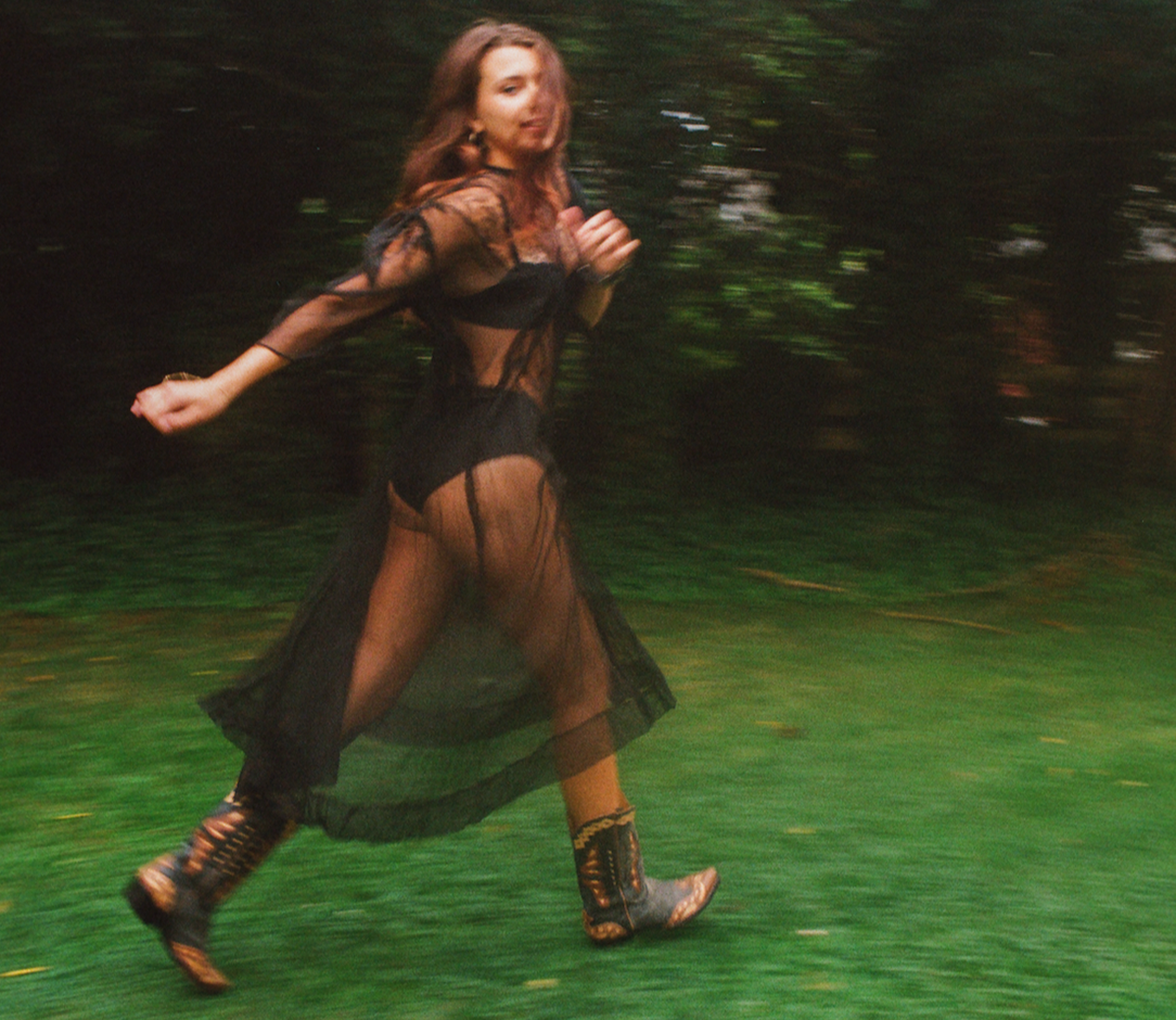 Person in a flowing dress running through a forest